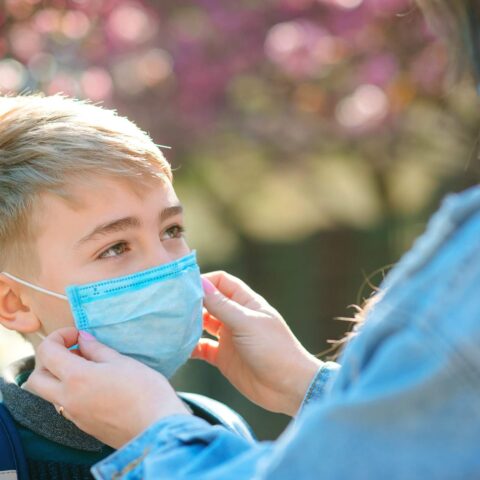 Mother Puts Her Son A Face Protective Mask Outdoors. Coronavirus